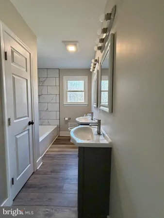 a bathroom with double vanity sink a mirror and a shower