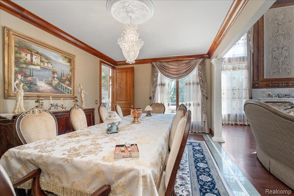 3543 Cedar Brook Drive Rochester, MI 48309 - Photo 35 of 99 Tray ceiling with a decorative medallion, crystal chandelier, wood-finish flooring, and a decorative archway