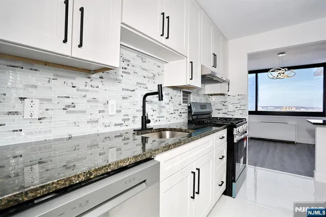 a kitchen with a sink a stove and a granite counter top