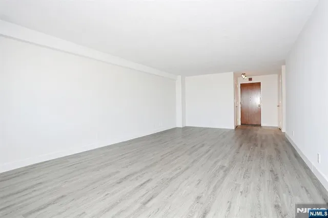 an empty room with wooden floor and bathroom