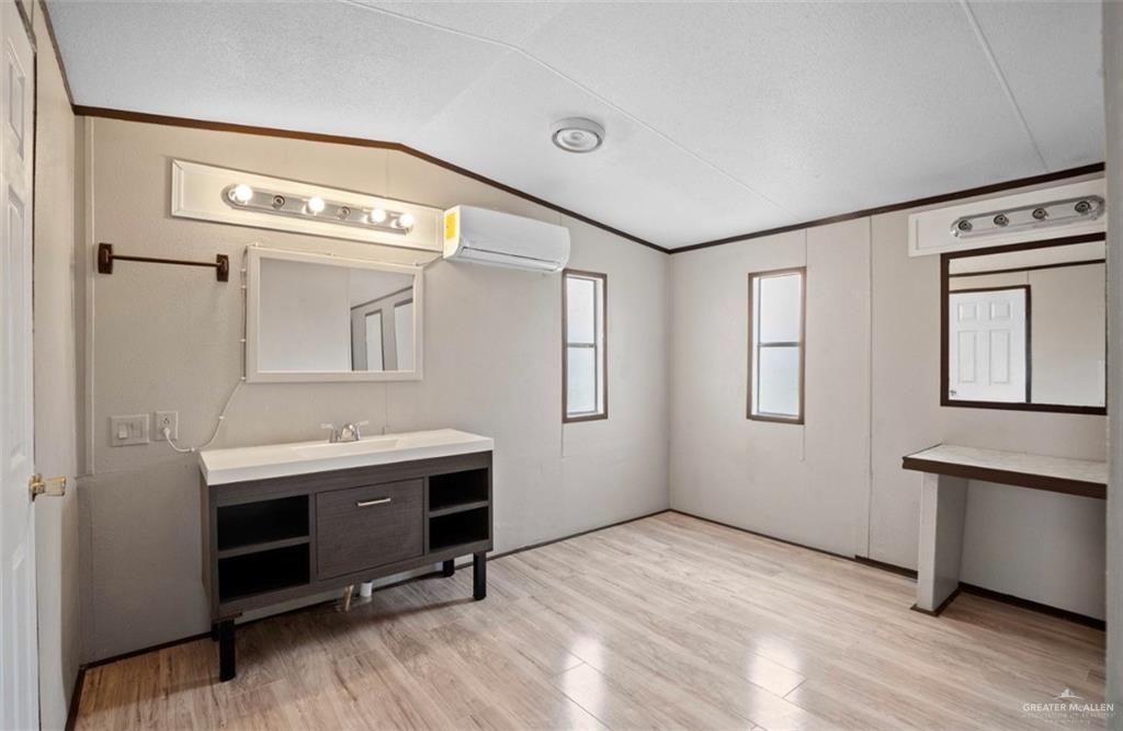 115 East Which Way Pharr, TX 78577 - Photo 11 of 20 Bathroom featuring vanity, light wood-style floors, a wall unit AC, vaulted ceiling, and ornamental molding