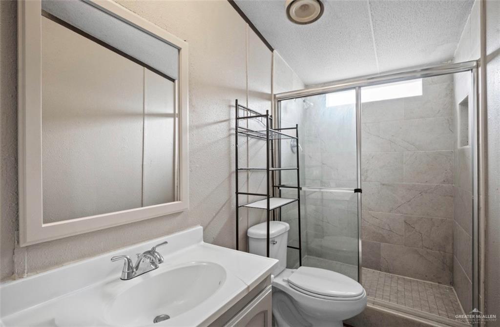 115 East Which Way Pharr, TX 78577 - Photo 16 of 20 Bathroom featuring a stall shower, vanity, and a textured ceiling
