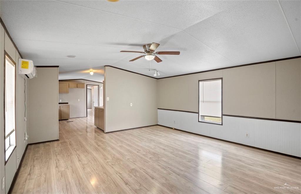 115 East Which Way Pharr, TX 78577 - Photo 4 of 20 Unfurnished room featuring a wall mounted air conditioner, a ceiling fan, a textured ceiling, ornamental molding, and light wood-style floors