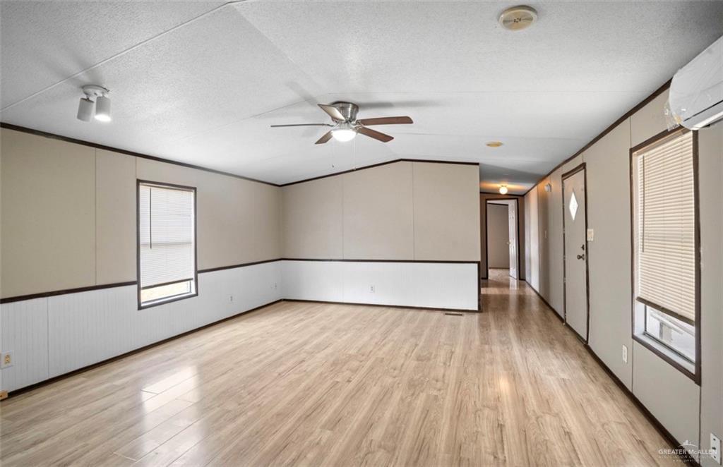 115 East Which Way Pharr, TX 78577 - Photo 5 of 20 Spare room featuring a textured ceiling, light wood-style flooring, a ceiling fan, ornamental molding, and a wall unit AC