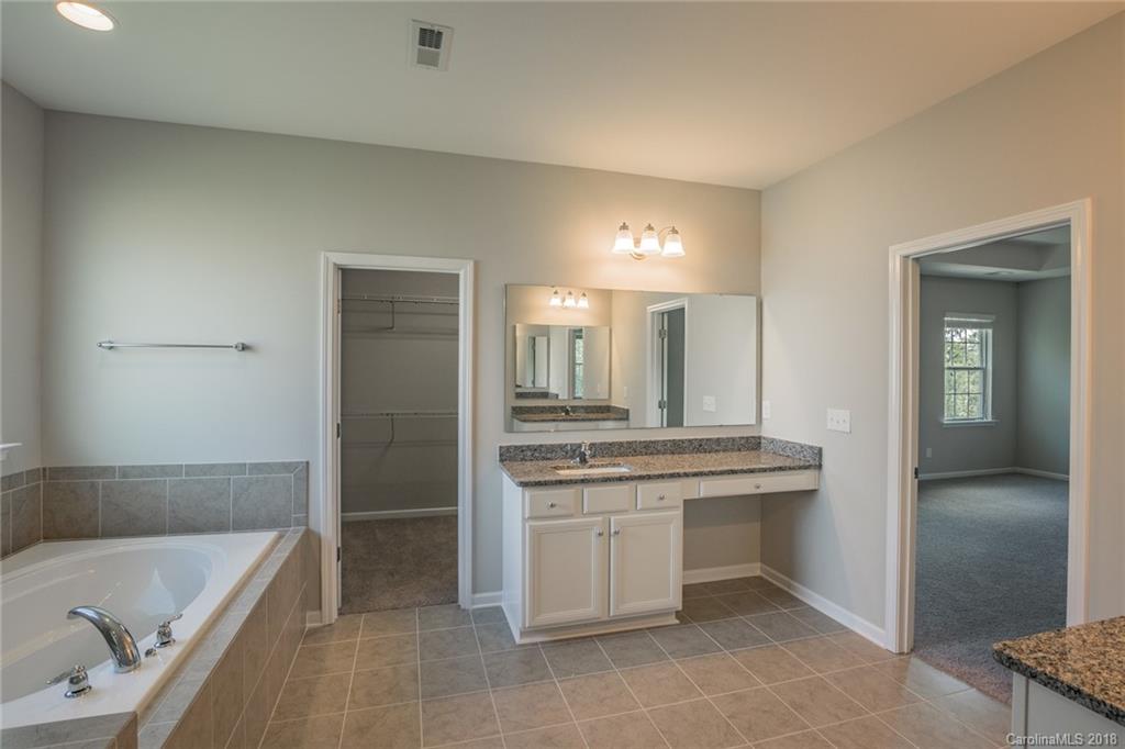5116 Waterloo Drive, Unit 60 Tega Cay, SC 29708 - Photo 23 of 36 a bathroom with a granite countertop sink a toilet and bathtub