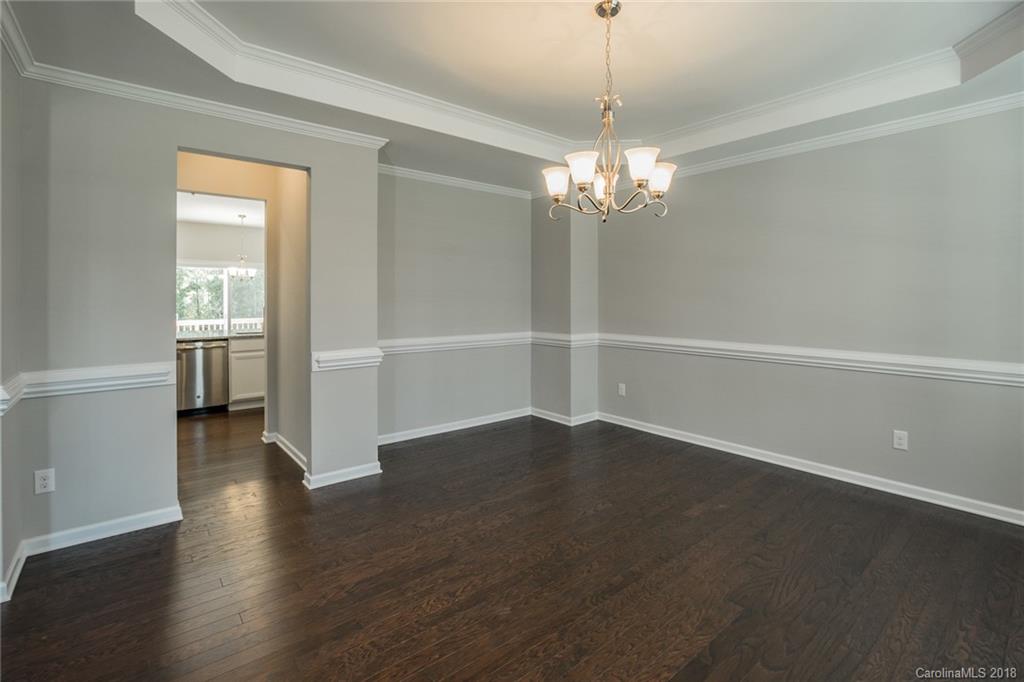 5116 Waterloo Drive, Unit 60 Tega Cay, SC 29708 - Photo 6 of 36 an empty room with wooden floor chandelier and windows