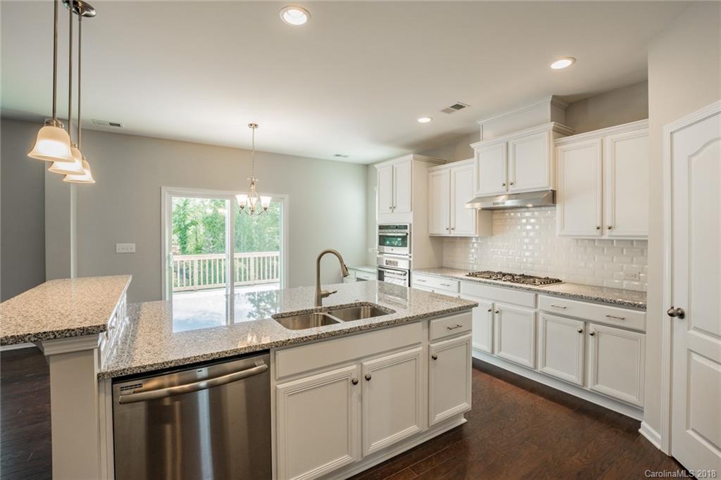 5116 Waterloo Drive, Unit 60 Tega Cay, SC 29708 - Photo 8 of 36 a kitchen with granite countertop a sink stainless steel appliances white cabinets and wooden floor