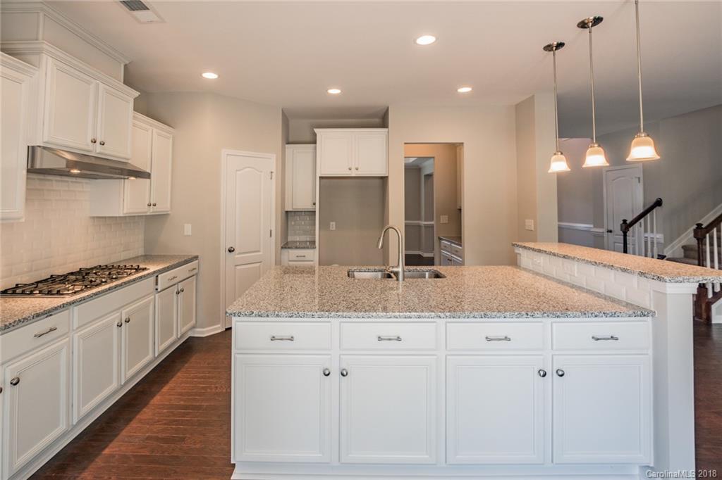 5116 Waterloo Drive, Unit 60 Tega Cay, SC 29708 - Photo 9 of 36 a large kitchen with kitchen island a stove a sink a center island and wooden floor