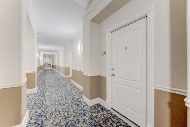 a view of a hallway with wooden floor and a bathroom