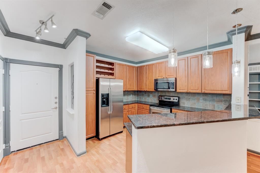 1711 Old Spanish Trail, Unit 110 Houston, TX 77054 - Photo 5 of 31 a kitchen with stainless steel appliances granite countertop a refrigerator a stove and a sink with wooden cabinets