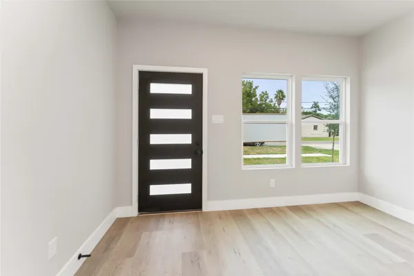 a view of an empty room with a window and wooden floor