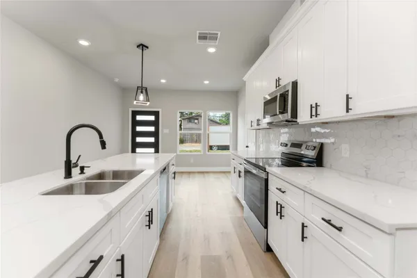 a kitchen with stainless steel appliances granite countertop a sink a stove and a wooden floors