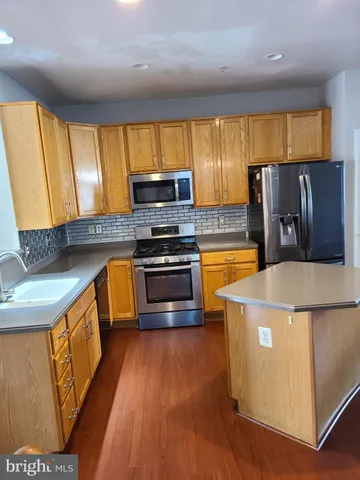 a kitchen with stainless steel appliances granite countertop a stove a sink dishwasher a microwave oven and a refrigerator with wooden floor