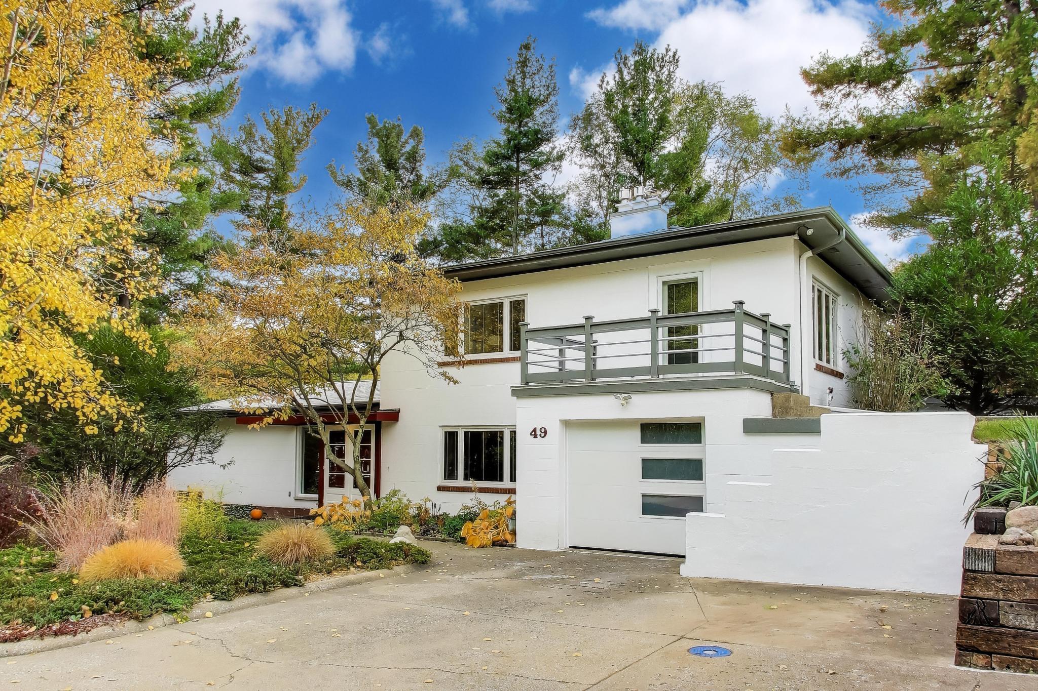 a view of a white house with a large tree and plants