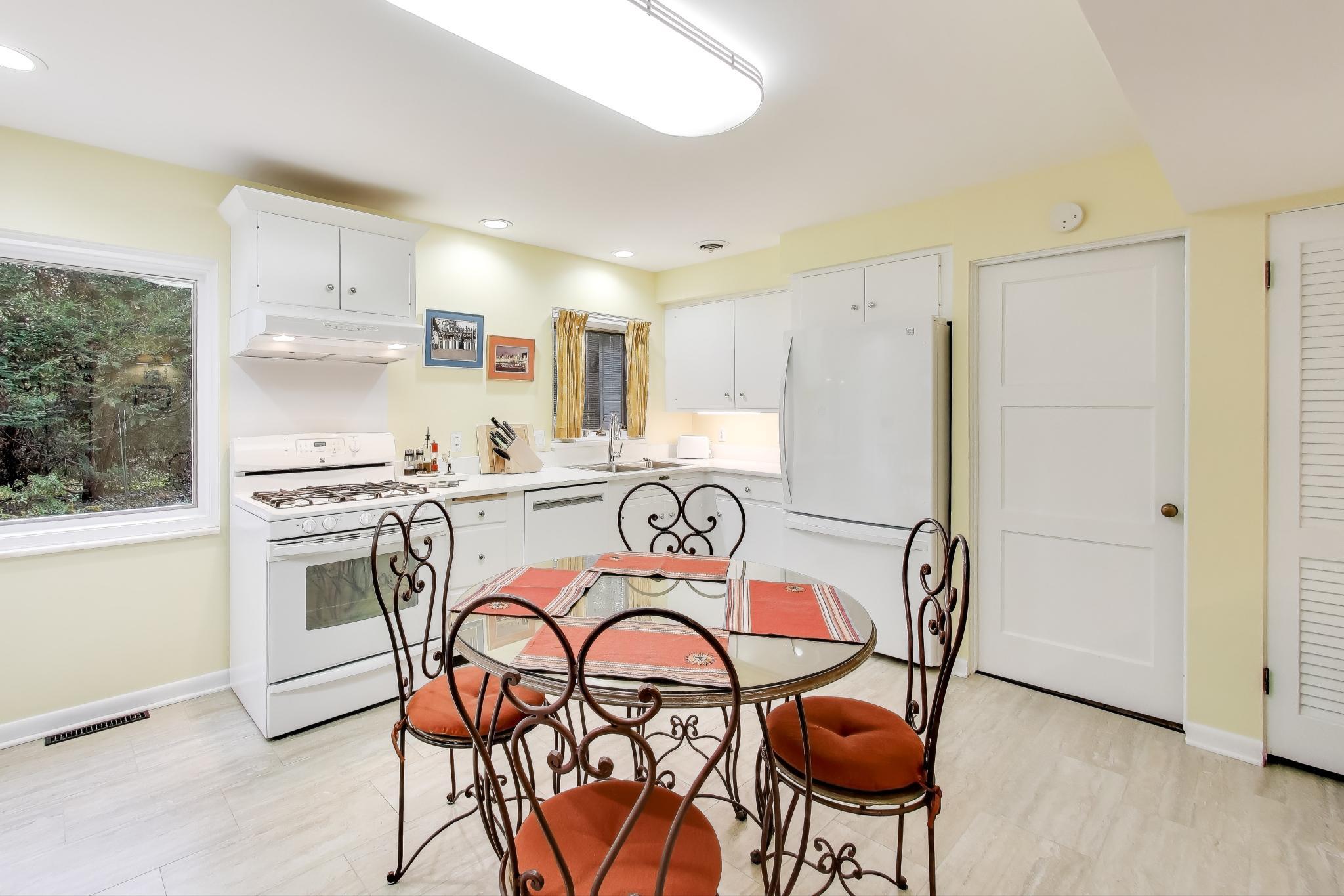 49 Aspen Road Ogden Dunes, IN 46368 - Photo 12 of 42 a white kitchen with stainless steel appliances granite countertop a dining table and chairs a refrigerator with wooden floors