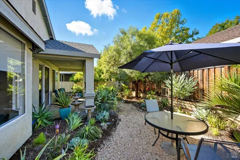 a backyard of a house with table and chairs under an umbrella