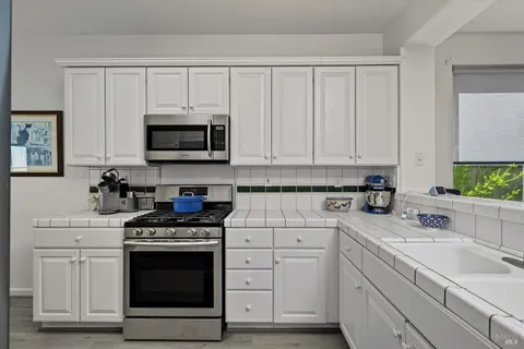 a kitchen with white cabinets and stainless steel appliances
