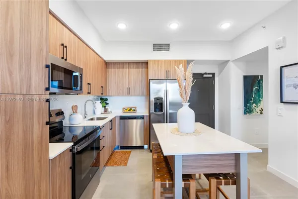 a kitchen with granite countertop a sink a counter top space stainless steel appliances and cabinets