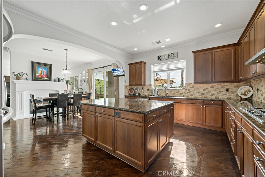 16423 Village Meadow Drive Riverside, CA 92503 - Photo 17 of 61 a kitchen with stainless steel appliances granite countertop a stove top oven a sink a dining table and chairs with wooden floor