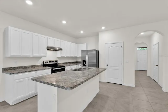 a kitchen with stainless steel appliances granite countertop a sink stove and refrigerator