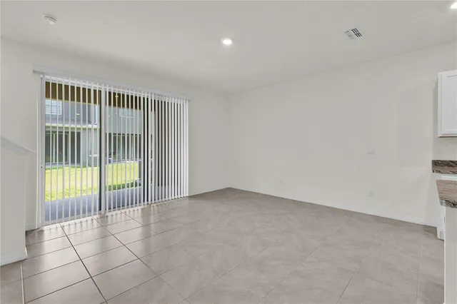 an empty room with kitchen view and a refrigerator