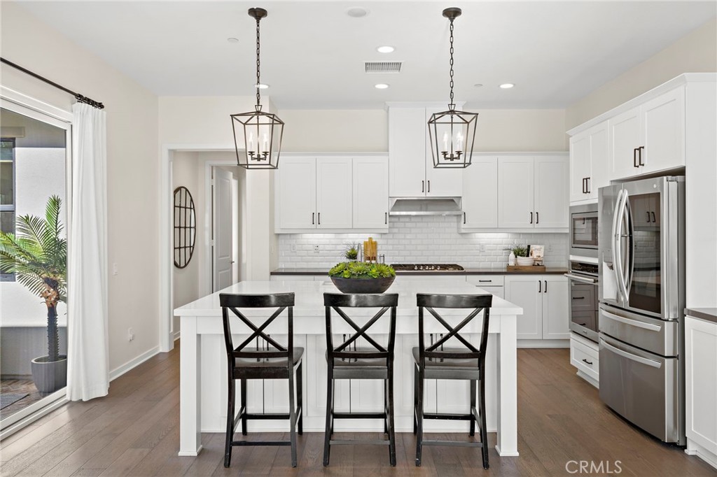 44 Jarano Street Rancho Mission Viejo, CA 92694 - Photo 11 of 65 a kitchen with stainless steel appliances kitchen island granite countertop a dining table chairs and white cabinets