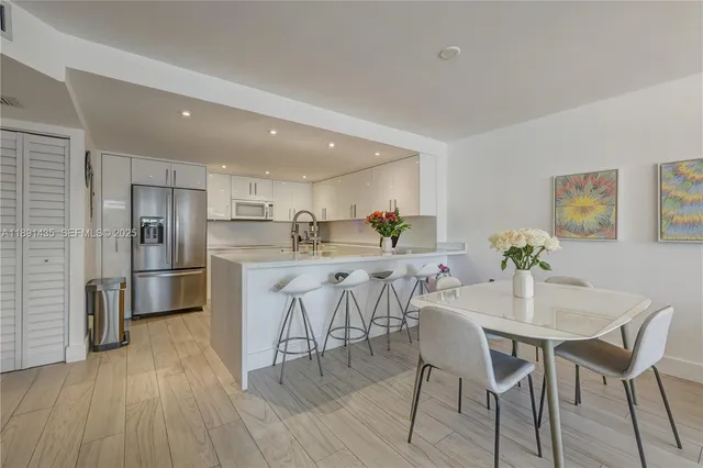 a kitchen with stainless steel appliances a dining table chairs refrigerator and sink