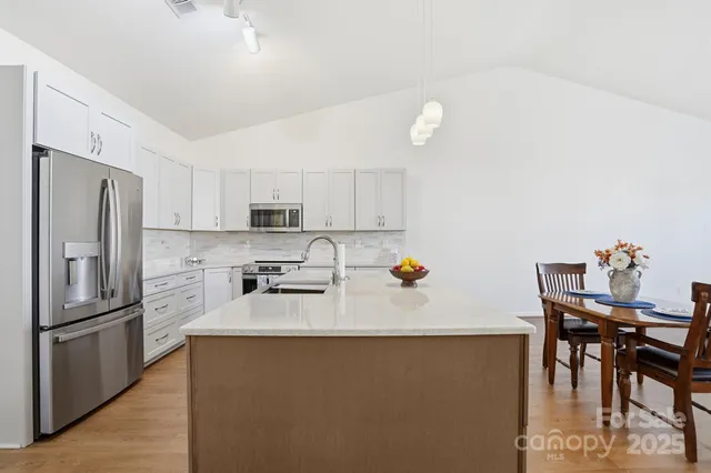 a kitchen with granite countertop a refrigerator and a stove top oven