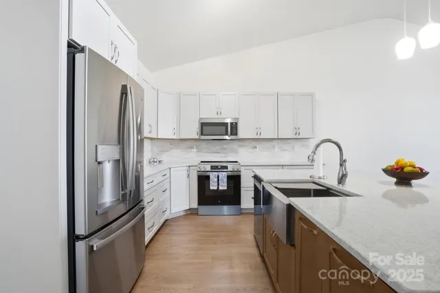 a kitchen with stainless steel appliances granite countertop a refrigerator and a stove top oven
