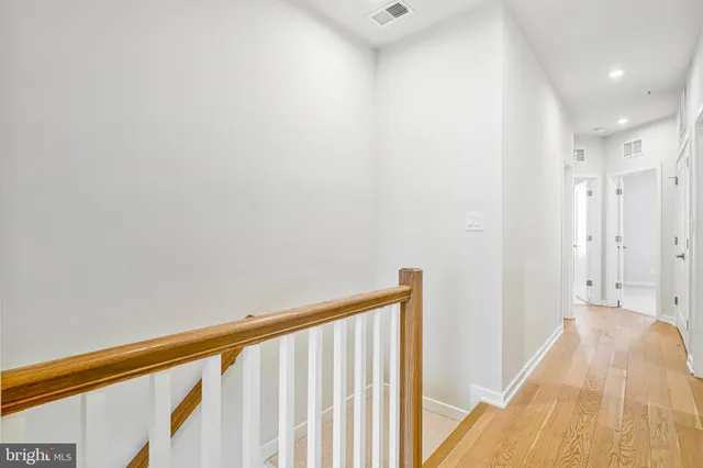 a view of a hallway with wooden floor and a bathroom
