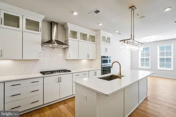 a kitchen with kitchen island granite countertop a sink a counter space appliances and cabinets