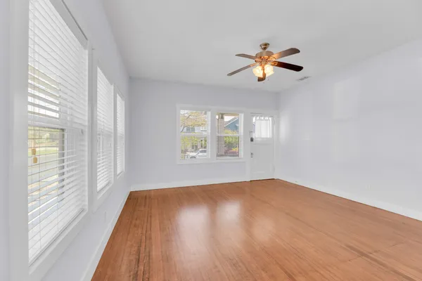 a view of empty room with wooden floor and fan