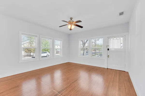 a view of an empty room with wooden floor and a window