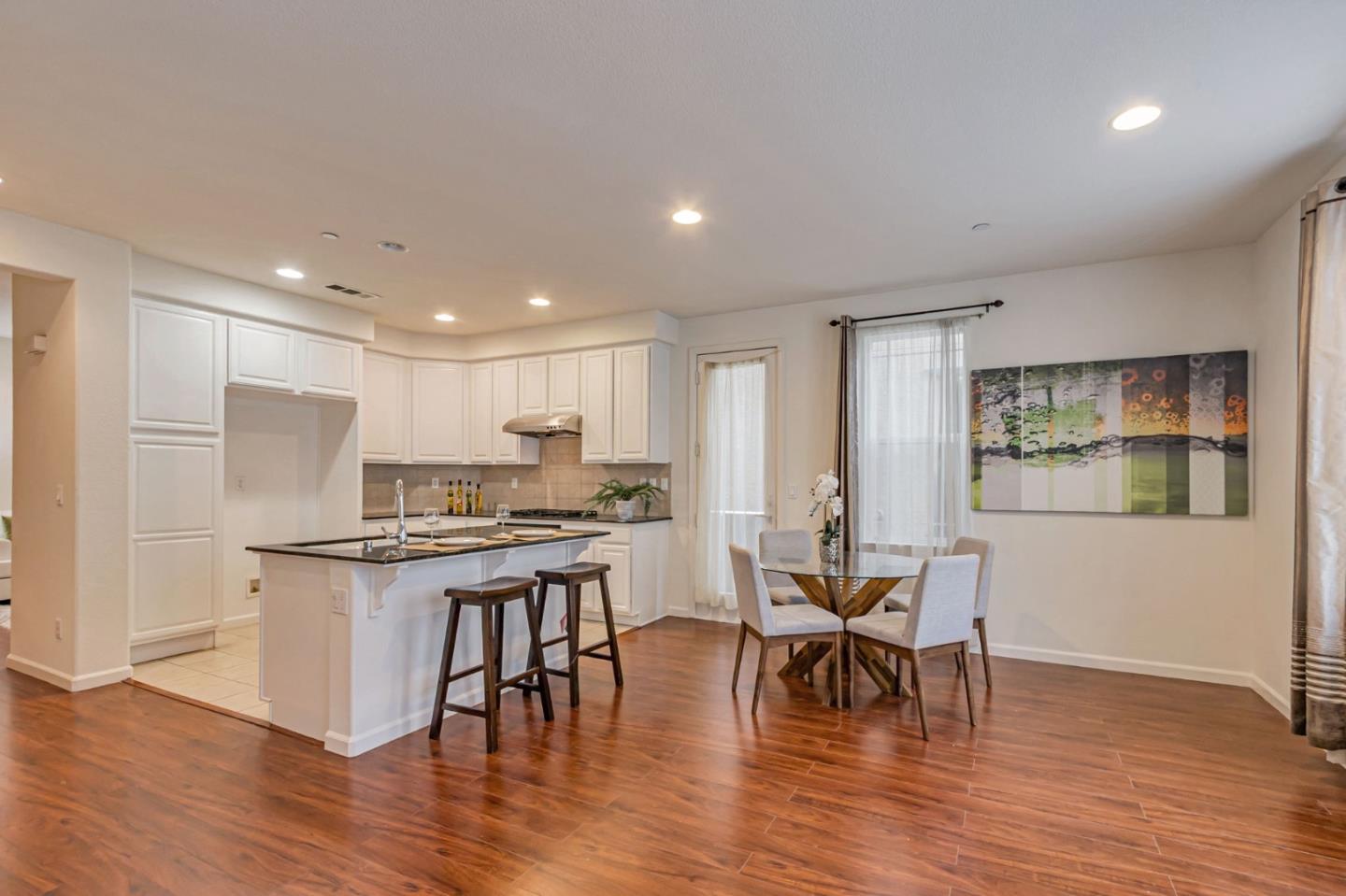 1103 Vida Larga Loop Milpitas, CA 95035 - Photo 13 of 44 a kitchen with stainless steel appliances granite countertop a stove top oven a sink a dining table and chairs with wooden floor