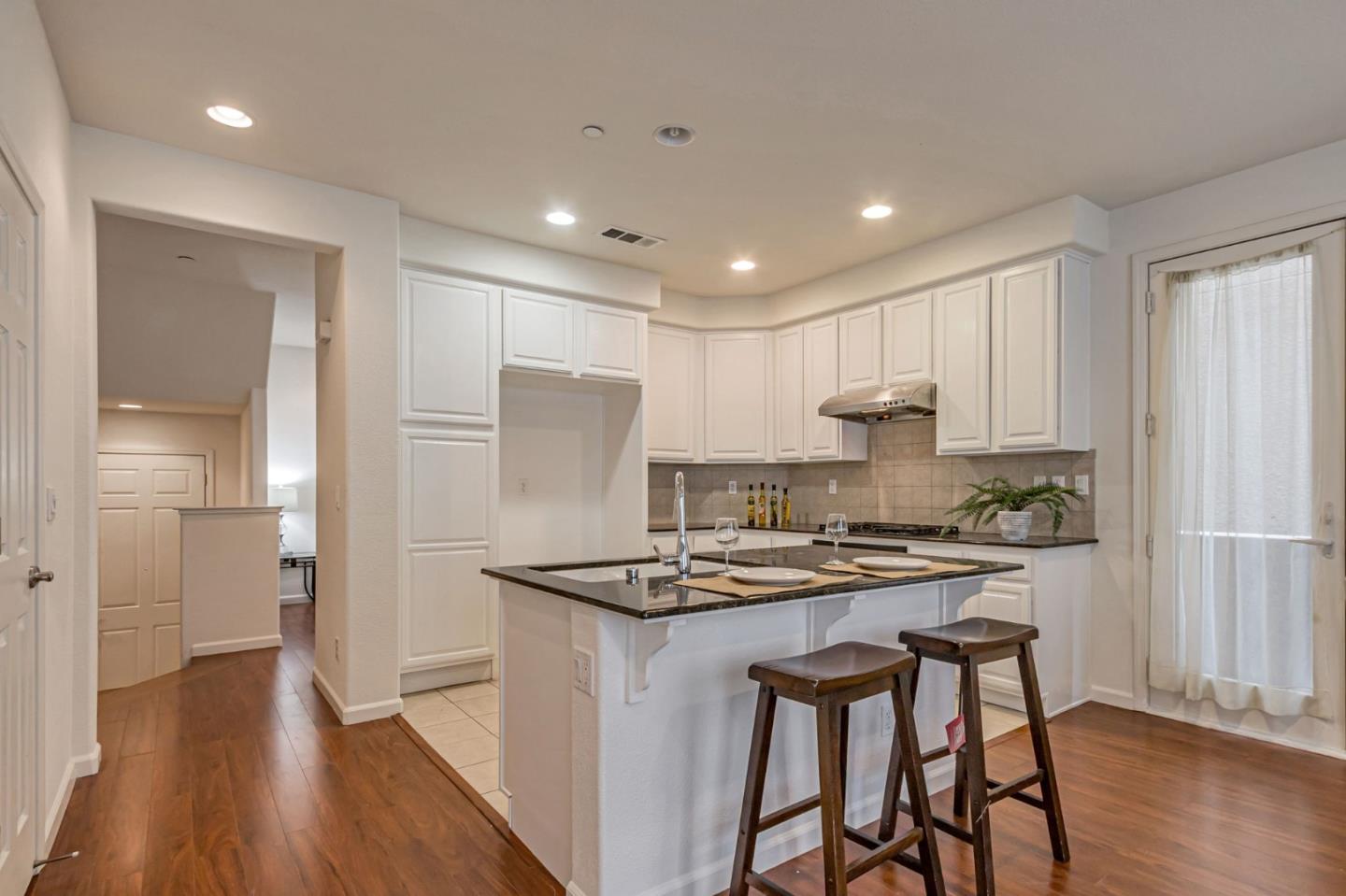 1103 Vida Larga Loop Milpitas, CA 95035 - Photo 10 of 44 a kitchen with stainless steel appliances granite countertop a stove a refrigerator and a dining table with wooden floor