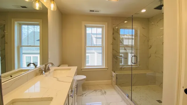 a bathroom with a granite countertop sink a toilet and shower