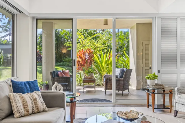 a living room with patio furniture and a potted plant