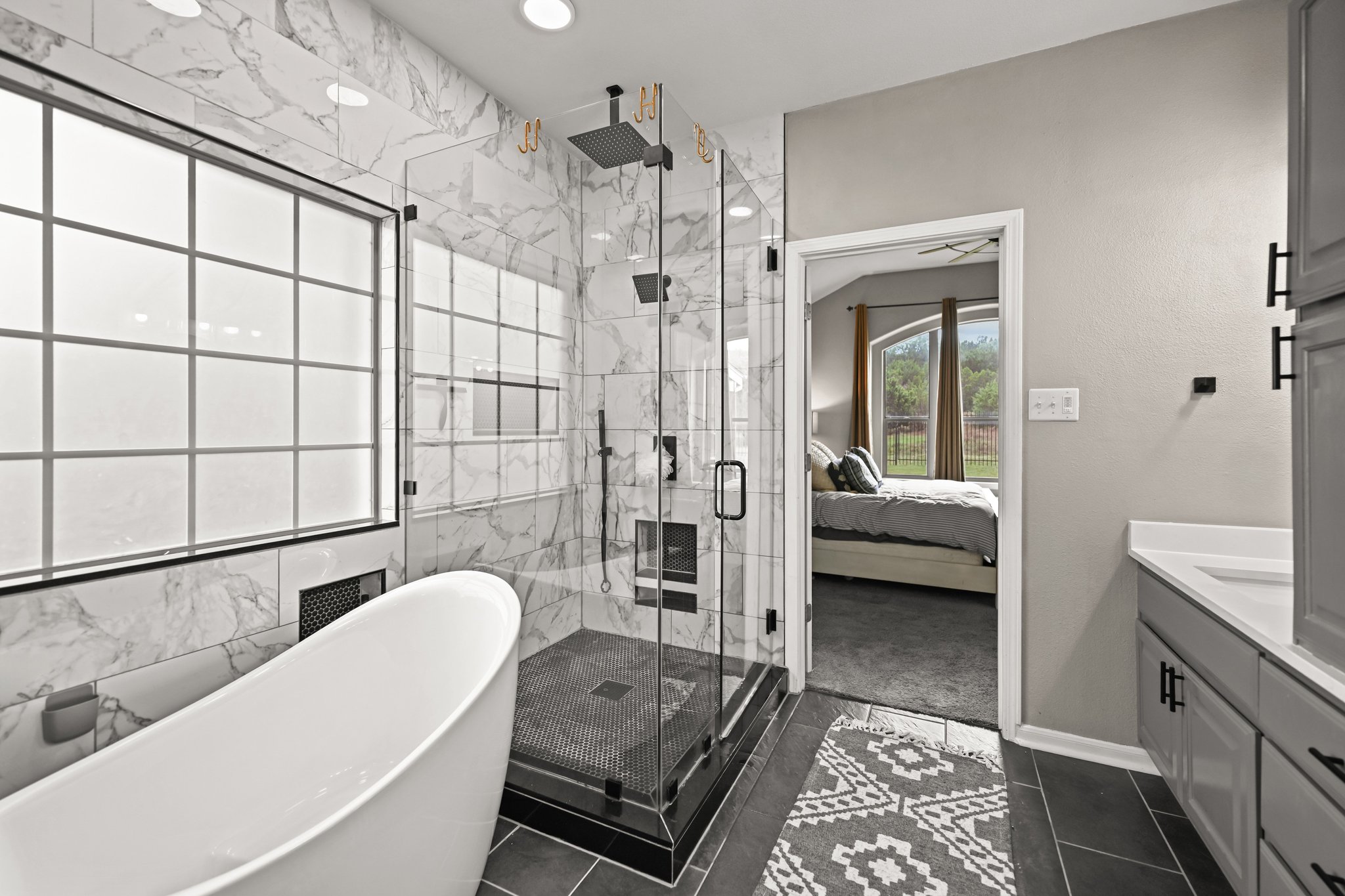 5528 Wild Foxglove Road Spicewood, TX 78669 - Photo 14 of 38 a en suite spacious bathroom with a granite countertop tub sink a mirror and shower