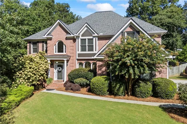 a front view of a house with a yard and trees