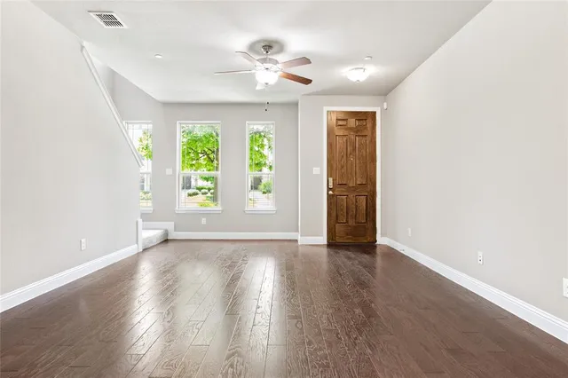 an empty room with wooden floor and windows
