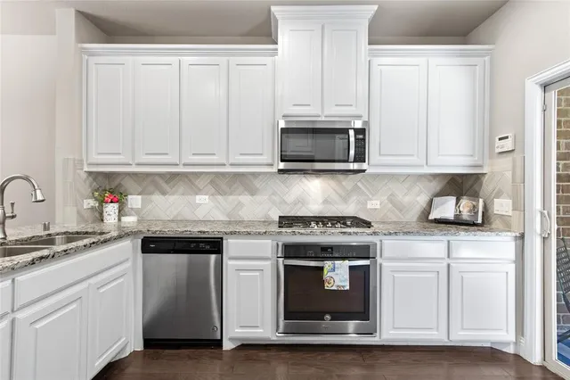 a kitchen with granite countertop white cabinets and stainless steel appliances