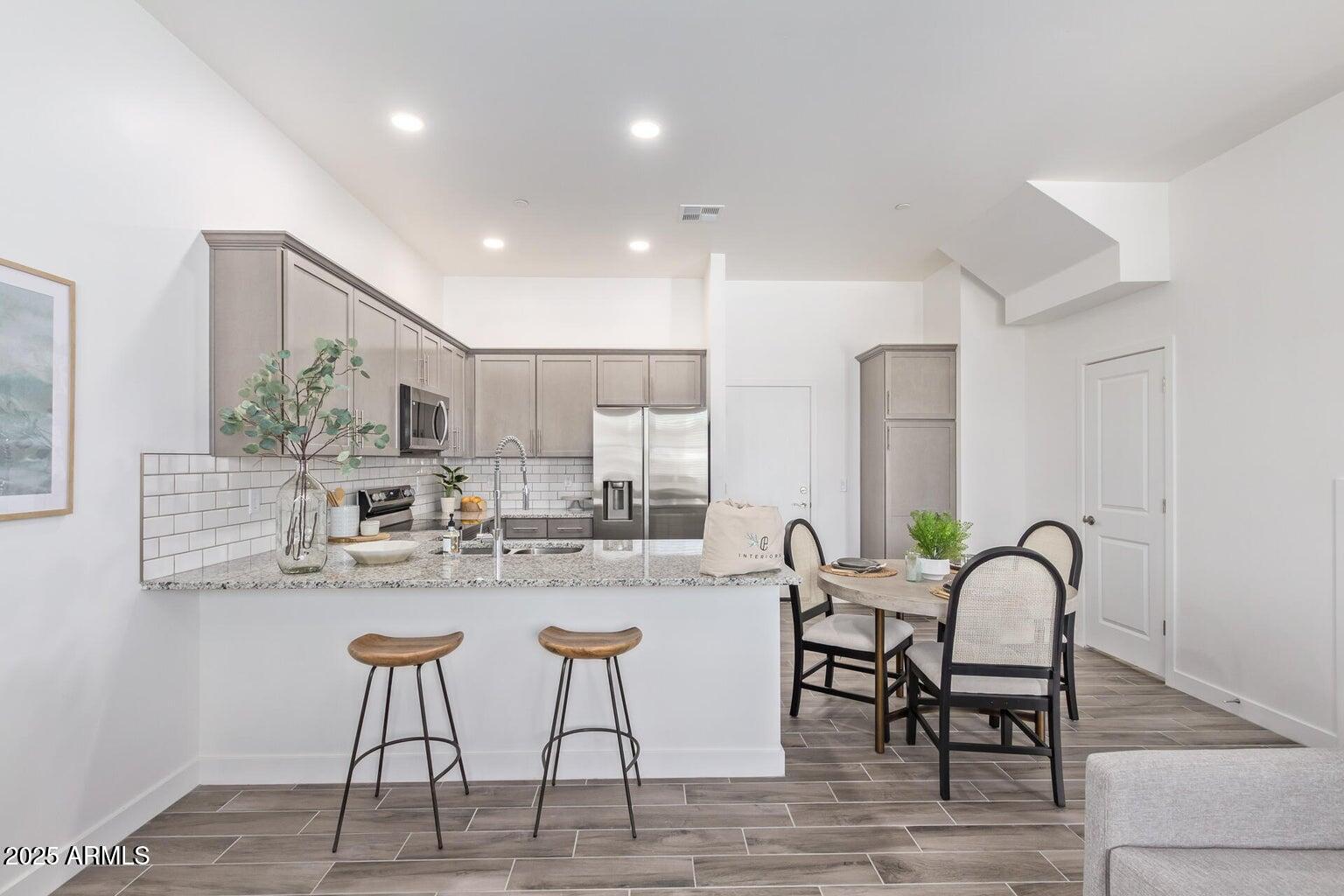 3230 East Thomas Road, Unit 168 Mesa, AZ 85213 - Photo 9 of 26 a kitchen with stainless steel appliances granite countertop dining table chairs and white cabinets