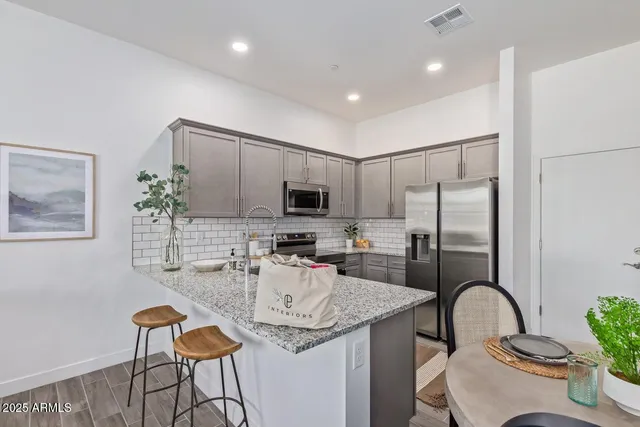 a kitchen with granite countertop stainless steel appliances a dining table chairs stove and sink