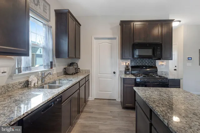 a kitchen with granite countertop kitchen island stainless steel appliances a sink stove and refrigerator