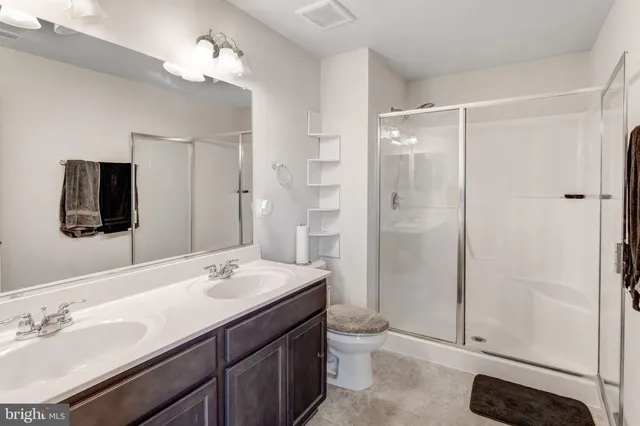 a bathroom with a sink a toilet a mirror and shower