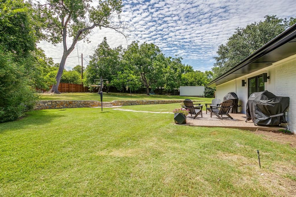 6700 Fortune Road Fort Worth, TX 76116 - Photo 35 of 40 Expansive backyard featuring a large lawn, tiered stone retaining walls, and mature trees