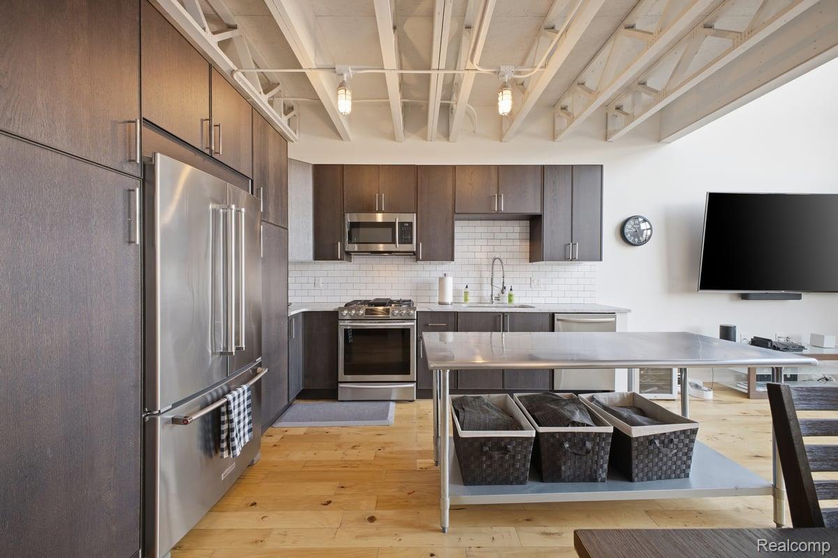 211 East 9 Mile Road, Unit 313 Ferndale, MI 48220 - Photo 5 of 40 Kitchen featuring stainless steel appliances, dark wood finish cabinets, light wood-type flooring, backsplash, and modern cabinets
