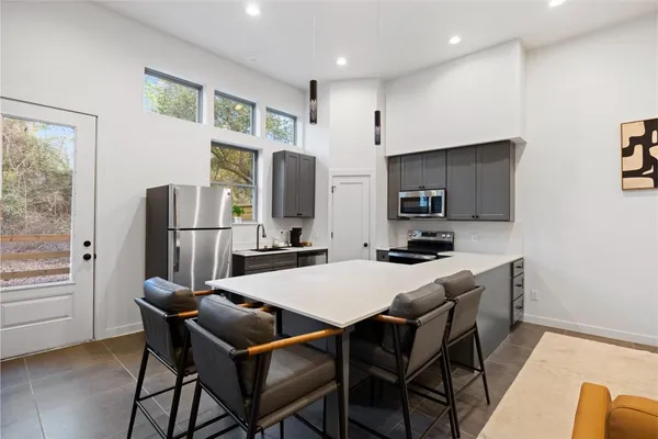 a kitchen with stainless steel appliances granite countertop a refrigerator a stove a microwave oven a sink dishwasher and white cabinets with wooden floor