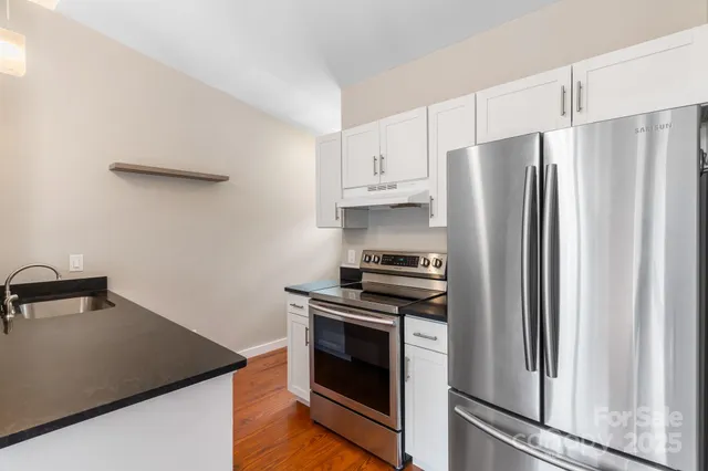 a kitchen with stainless steel appliances a refrigerator a stove and white cabinets