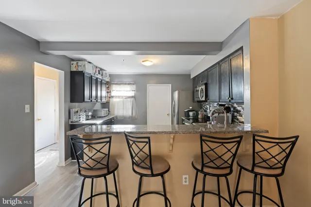 a kitchen with stainless steel appliances kitchen island granite countertop a table and chairs in it